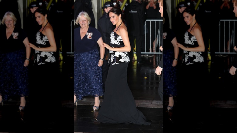 Meghan Markle marche vêtue d'une jupe longue noire et d'un haut à sequins monochromes