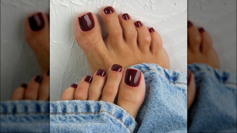 Une pédicure avec du vernis à ongles bordeaux foncé