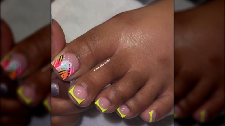 Une pédicure aux pointes françaises fluo et au design multicolore des années 90
