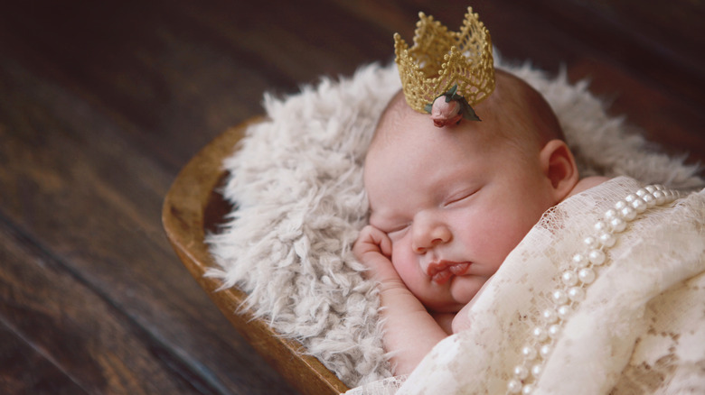 Petite fille dormant avec un diadème et une couverture de perles