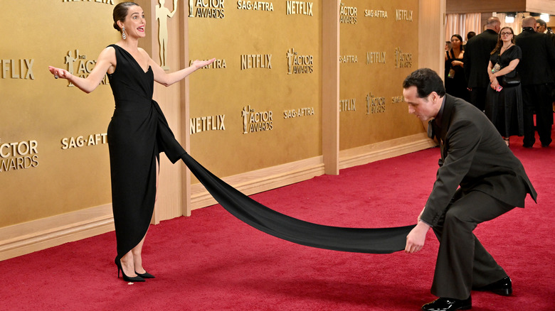 Keri Russell pose sur le tapis rouge pendant que Matthew Rhys répare la traîne de sa robe