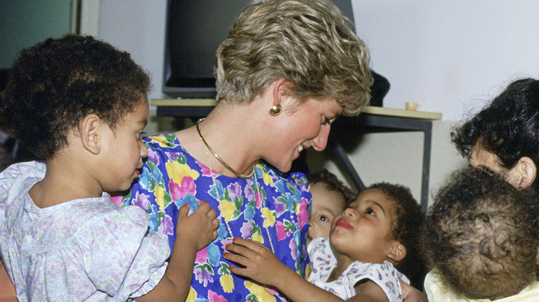 La princesse Diana porte une robe à fleurs colorée serrant ses enfants dans ses bras au Brésil.