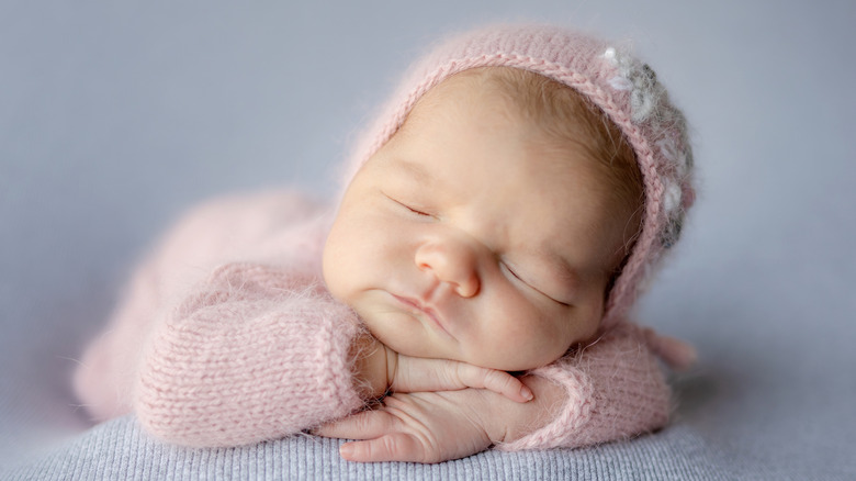 Un nouveau-né dormant dans une tenue rose et un bonnet