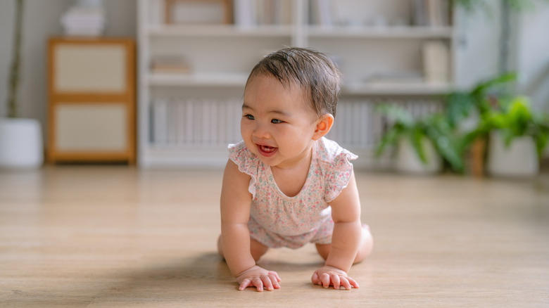 Une petite fille dans une barboteuse qui rampe