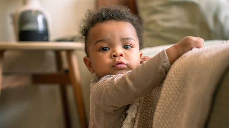 Un bébé debout contre un canapé
