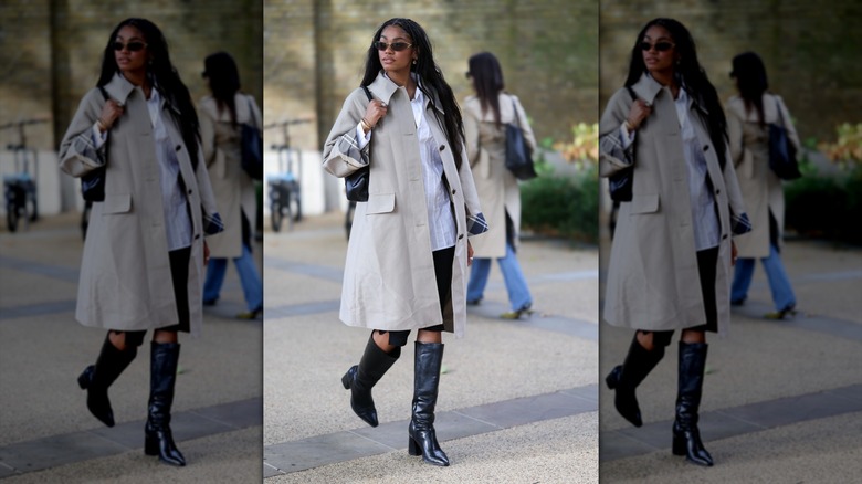 Une femme portant un trench beige et des bottes en cuir noir