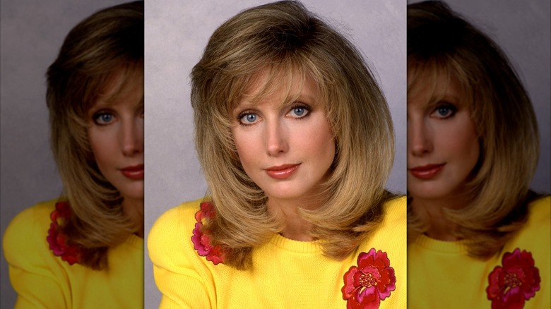 Morgan Fairchild dans un portrait de 1990 portant un pull jaune aux accents floraux rouges.