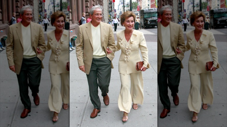 Judy Sheindlin marche avec son mari (à gauche) vêtue d'un pantalon large et d'un chemisier à volants