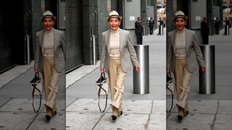 Judy Sheindlin porte un fedora beige et noir avec un col roulé crème et un blazer gris.