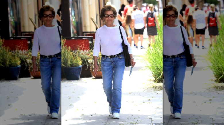 Judy Sheindlin porte un jean évasé et une chemise à manches longues blanche avec une ceinture noire