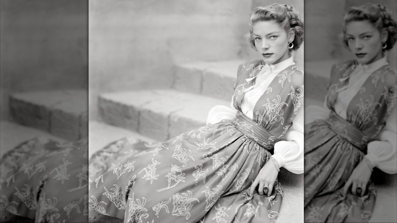Lauren Bacall se prélasse dans les escaliers dans une blouse blanche et une robe chasuble à imprimé floral pour le magazine Glamour en août 1949