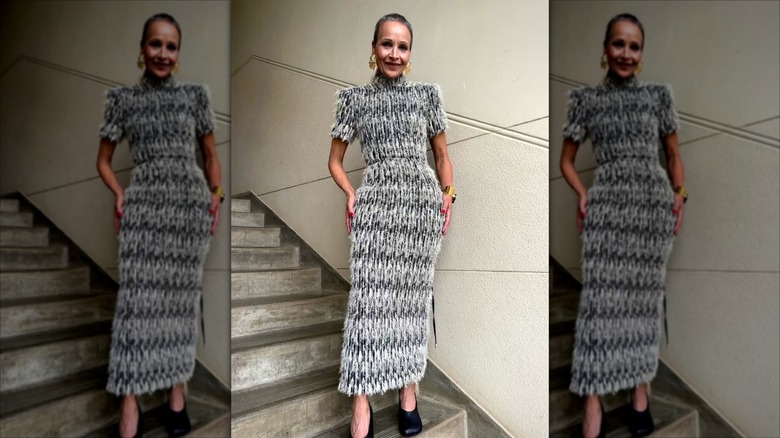 Yasmin Furmie porte une robe longue ornée de plumes et de bijoux dorés