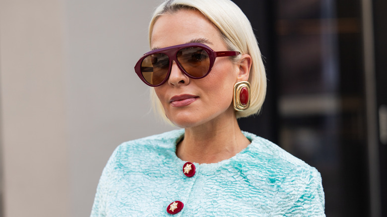 Une femme portant des boucles d'oreilles rectangulaires avec des pierres précieuses rouges.