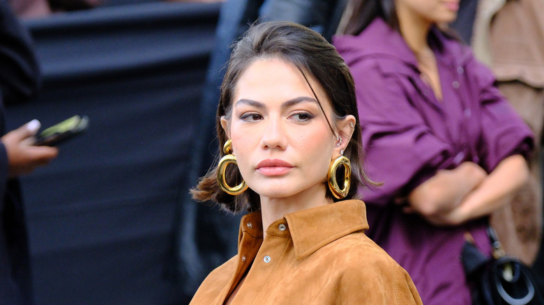 Une femme avec de grandes boucles d'oreilles volumineuses.