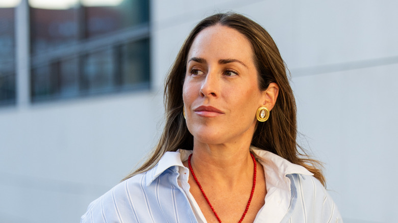 Une femme portant des boucles d’oreilles boutons en or et cristal.