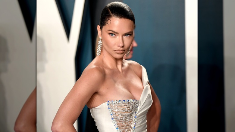 Adriana Lima porte une coiffure lissée en arrière et une robe asymétrique à la Vanity Fair Oscar Party en 2020.