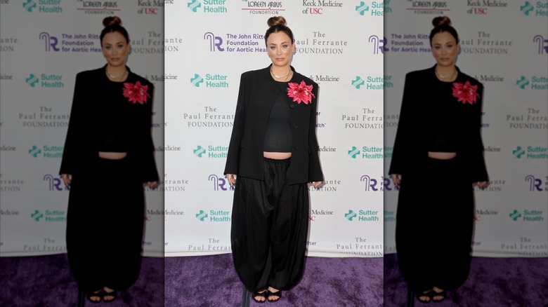 Kaley Cuoco sourit dans un costume noir