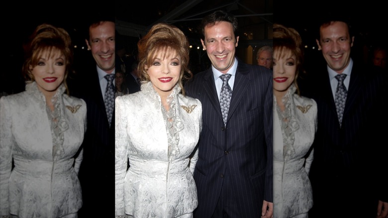 Joan Collins porte un tailleur jupe blanche à côté de Percy Gibson en costume