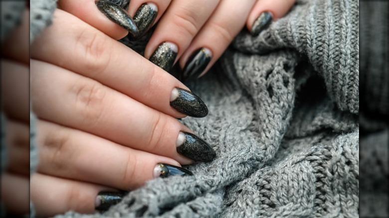 Une manucure demi-lune avec du vernis à paillettes foncées.