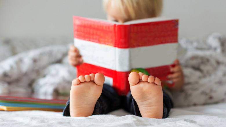 Une photo montre un enfant flou alors qu’il lit un livre à rayures rouges et blanches